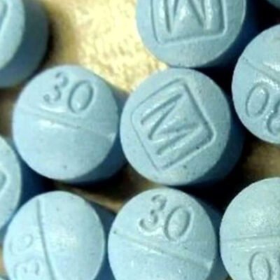 Blue round Oxycodone M30 tablet marked with 'M' on one side and '30' on the other, used for treating severe pain.
